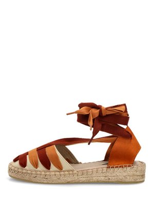 Sandalia plana tipo esparto con suela beige, tiras de tela en naranja y óxido, y cordones para el tobillo en colores a juego.
