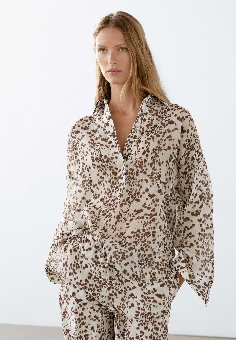 Lätt, beige blus i lös passform med bruna leopardfläckar, med krage och knytning i midjan, mjuk textur.
