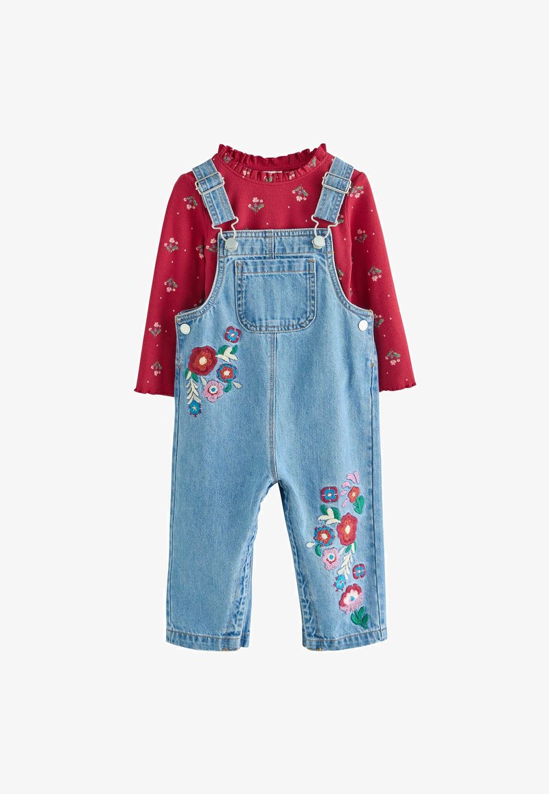 Salopette en denim avec broderie florale en rose, rouge et vert sur le devant ; associée à un haut rouge à côtes présenté avec un col volanté et un imprimé floral.