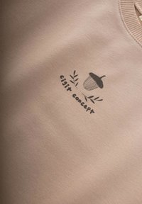 Sudadera beige claro con una ilustración de una bellota negra y el texto "cijit concept." Textura suave con un cuello redondo.