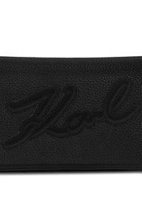 Clutch in pelle nera con superficie testurizzata e logo "Karl" in rilievo dello stesso nero. Forma sottile e rettangolare con linee pulite.