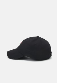 Gorra de béisbol de algodón negra con visera curva, correa ajustable y detalle del logotipo bordado en el costado. Textura suave con acentos cosidos.