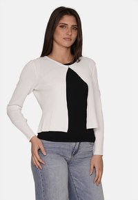Cardigan bianco a maniche lunghe con un design cropped, caratterizzato da un pannello nero asimmetrico sul davanti. Tessuto liscio, chiusura frontale aperta.