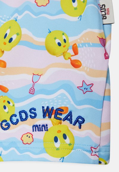 Tecido colorido com pássaros amarelos em cartoon sobre um fundo azul claro com padrões ondulados. Texto bordado em azul lê "GCDS WEAR mini."