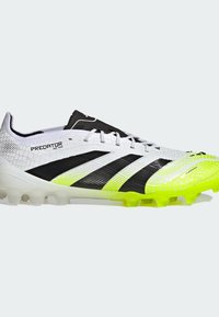 White and black synthetic soccer cleat with yellow accents, textured upper, aerodynamic design, and six molded studs for traction.