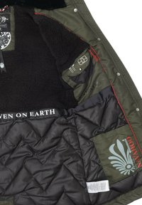 Olive green jacket interior with black fleece lining, quilted black fabric, red accents, and multiple pockets. Brand logo on the lining.