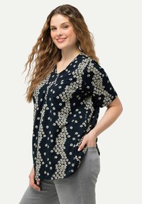 Námořnická blůza s bílým květinovým vzorem, krátkými rukávy a výstřihem do V. Měkká látka s uvolněným střihem a bočními kapsami.