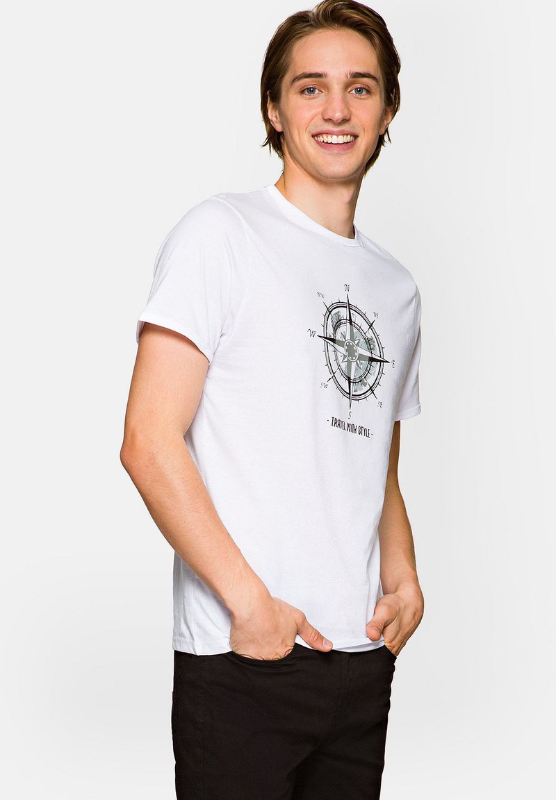 Biała bawełniana koszulka z grafiką kompasu w odcieniach szarości, krótki rękaw, okrągły dekolt, w zestawie z czarnymi spodniami.