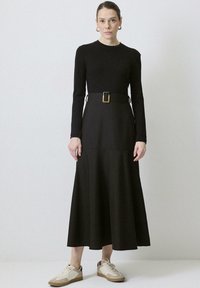 Must mustriga must dress, millel on kehasüda, laienev seelik ja kuldne vööklamber. Sobitatud beeži ja valge tossudega.