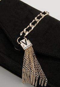 Clutch in suede nero con tracolla a catena dorata e dettaglio con nappina. Presenta una targhetta con il logo "VALENTINO" e dettagli testurizzati sulla superficie.