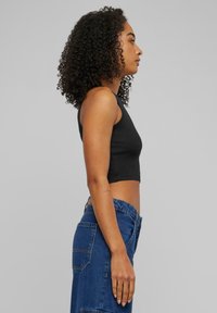 Zwarte cropped tanktop gecombineerd met een hooggesneden blauwe denimrok. De top heeft een getailleerd ontwerp met een soepele textuur.