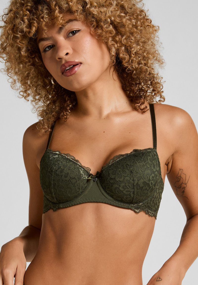 Olivgrüner Spitzen-BH mit Unterwire, ausgestattet mit einer gewellten Spitzenrand und einer Schleifen-Detail in der Mitte. Verstellbare Träger und eine glatte Textur.