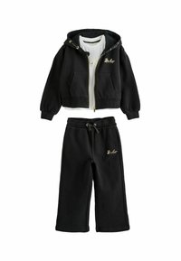 Sudadera negra con detalles en dorado y bolsillos frontales, combinada con pantalones de chándal negros a juego que tienen una cintura elástica y un detalle del logo.