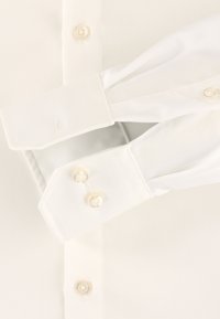 Witte shirt met puntkraag, barrel cuffs met twee knopen en een gladde, glanzende textuur. Stof lijkt fris en schoon.