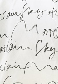 Tela blanca con texto manuscrito en negro, fluido, que presenta un grosor de línea variable y un estilo cursivo, creando un patrón orgánico.