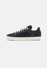 Sorte suede sneakers med hvid syning, snørrebåndsdesign og gummisål. Har en polstret krave og diskret branding på tungen.