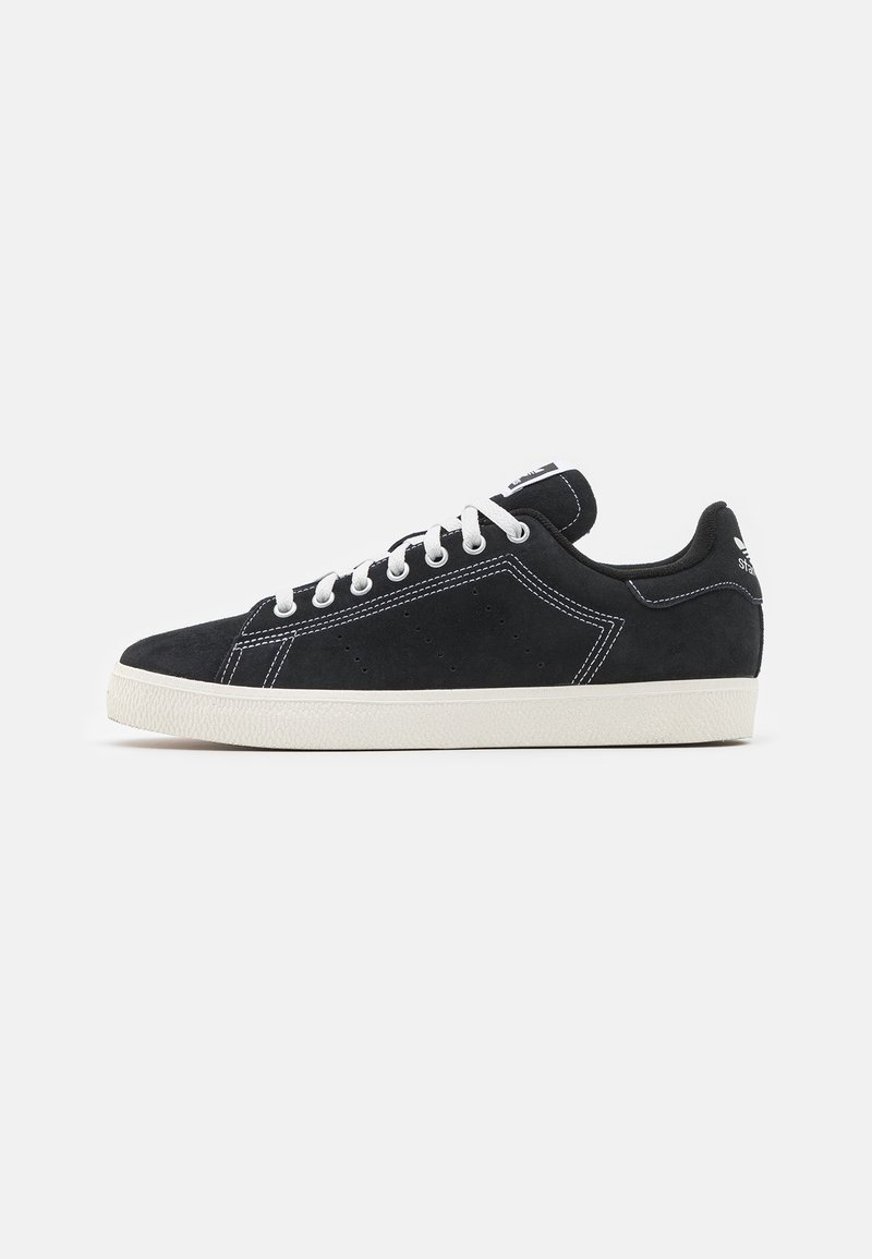 Sorte suede sneakers med hvid syning, snørrebåndsdesign og gummisål. Har en polstret krave og diskret branding på tungen.