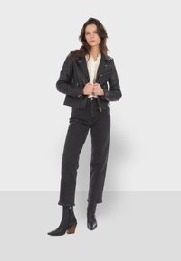 Black leather biker jacket with silver zippers, paired with high-waisted black jeans and pointed toe ankle boots with a block heel.