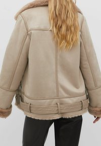 Beige faux suede jacket with a fluffy collar, gathered waist, and textured sleeves. Features soft fur accents at cuffs and hem.
