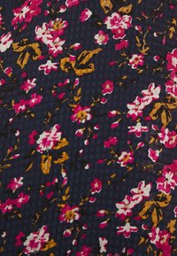 Tmavá tkanina se květinovým vzorem s růžovými, bílými a žlutými květinami na námořnickém modrém pozadí. Textura se slabými kostkovanými prvky.