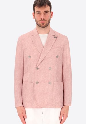 Uomo che indossa un blazer doppiopetto color rosa chiaro con sei bottoni, tasche applicate e una camicia bianca sotto, su uno sfondo neutro.