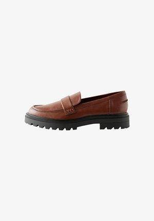 Mocassino in pelle marrone con punta arrotondata, dettagli cuciti e suola in gomma crepe con profonde scanalature per una buona trazione. Design informale.