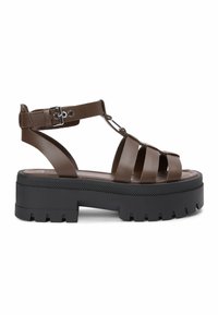 Sandale gladiateur en cuir marron avec semelle plateforme noire à grosse semelle crantée et bride de cheville avec boucle argentée.