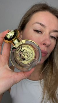 Guess Bella Vita parfum in een doorzichtige glazen fles met een gouden dop. Heeft een bloemachtige gravure aan de basis en een ronde, reflecterende oppervlakte.