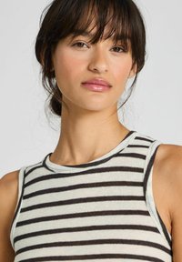 Top a righe in crema chiaro e marrone scuro. Caratterizzato da un collo tondo e un design senza maniche, realizzato in un tessuto morbido e leggero.