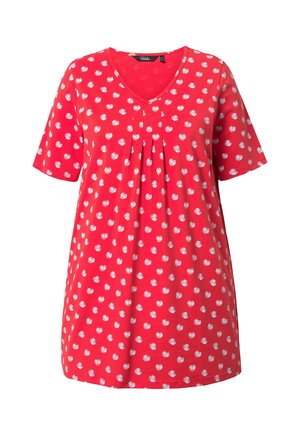 Czerwona tunika w białe kropki, z krótkimi rękawami, dekoltem w serek i plisami z przodu, przedstawiona na jednolitym białym tle.