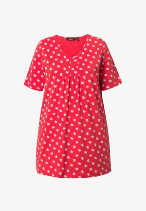 Punainen tunikapaita valkoisilla pilkuilla, lyhyet hihat, V-aukko ja etuosan laskokset, esillä yksinkertaisella valkoisella taustalla.