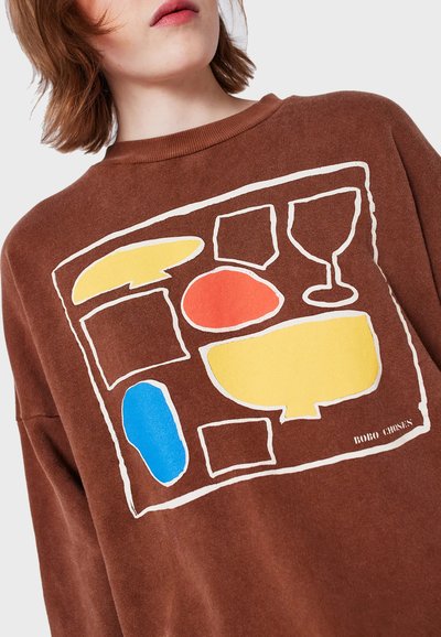 Brun sweatshirt med en grafisk design med färgglada former i gult, rött, blått och svarta konturer. Mjuk textur, avslappnad passform.