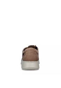 Zapatilla de ante beige con punta redondeada, suela blanca en contraste y detalles de costura decorativa. Presenta un diseño sin cordones para facilitar su uso.