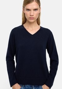 Granatowy sweter w serek z miękkiego dzianiny, z długimi rękawami i dopasowanym dołem, charakteryzujący się gładką fakturą i minimalystycznym designem.