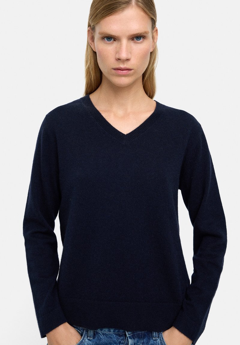 Granatowy sweter w serek z miękkiego dzianiny, z długimi rękawami i dopasowanym dołem, charakteryzujący się gładką fakturą i minimalystycznym designem.