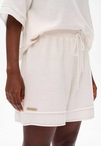 Witte gebreide shorts met een textuurpatroon, voorzien van een elastische tailleband en een trekkoord, afgewerkt met een klein, gouden label met de tekst "blue shadow."