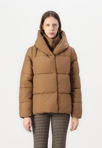 Giacca puffer marrone con colletto alto e cappuccio oversize. Presenta un design trapuntato con sezioni rettangolari, realizzato in un materiale liscio e opaco.