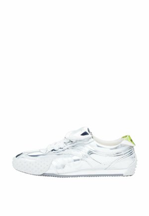 Shiny silver low-top sneaker with white sole, white laces, and a small neon green pull tab at the heel.