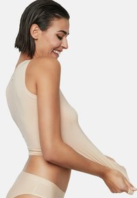 Haut nu, transparent, sans manches, avec une texture lisse, un design ajusté et un col rond. Le tissu semble léger et extensible.