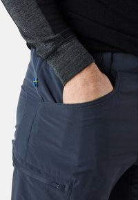 Navy blue pants with a textured black long-sleeve top, featuring a Swedish flag patch on the left pocket and a zipper pocket design.