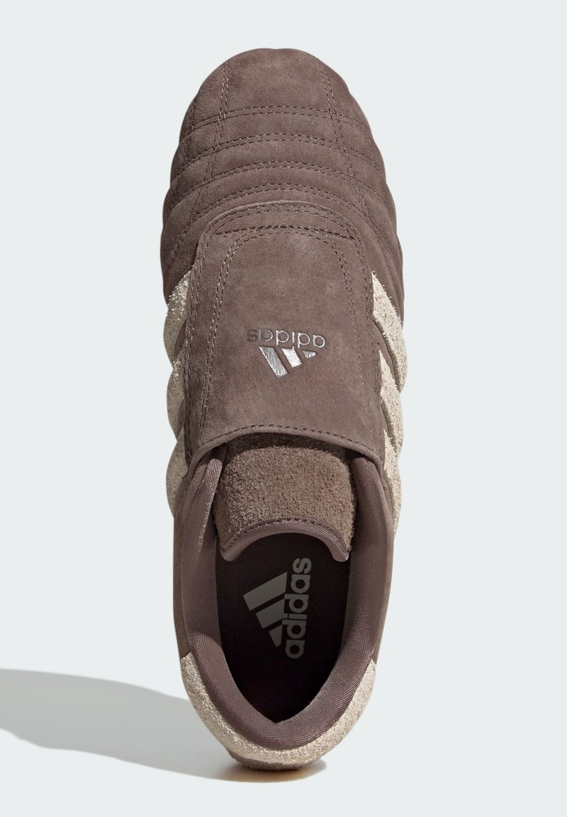 Zapatillas de ante marrón con tres rayas beiges, parte superior texturizada y puntera redonda. El logo de Adidas aparece en el lateral y en el interior del zapato.