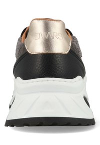 Zwarte leren en grijze textiel sneaker met een goudkleurige metalen hieltab, voorzien van een witte zool en textuuraccenten. Logo is zichtbaar op de hiel.