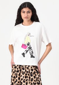 Hvit T-skjorte med grafikk av en figur i en gul topp og svarte blomstrete bukser, som holder en rosa håndveske. Behagelig passform, oversized ermer.