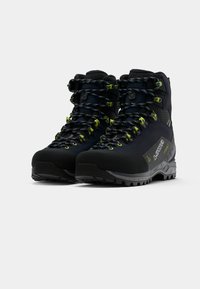 Botas de caminhada pretas com detalhes em amarelo e cinza, apresentando um design de tornozelo alto, superfície texturizada e uma sola de borracha com cravos para tração.