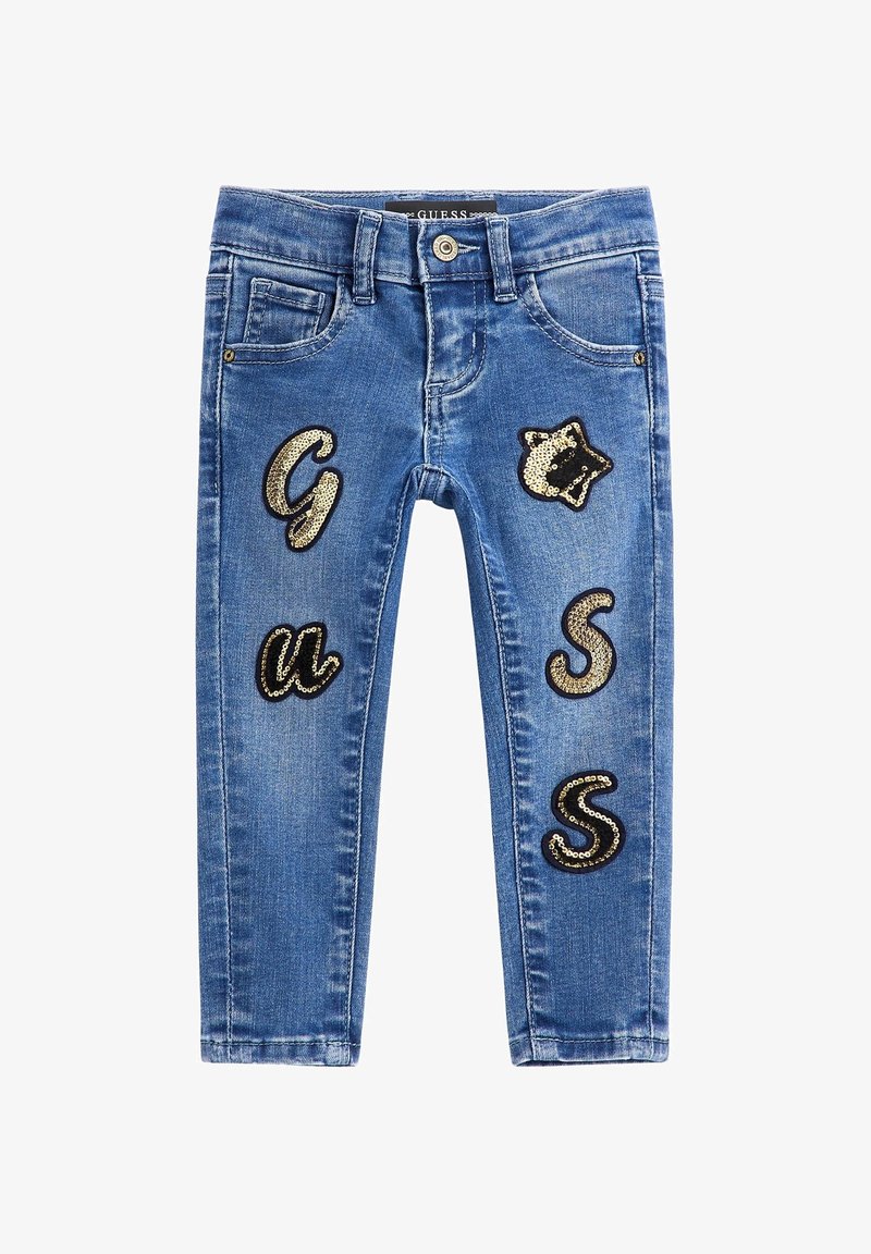 Jeans en denim bleu avec une coupe slim. Présente des lettres en sequins dorés "G," "u," "S," et "S" appliquées à l'avant. Comprend des poches et une fermeture à bouton.