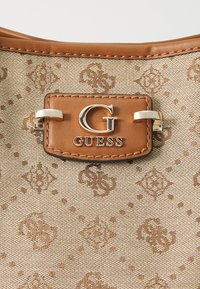 Torebka w brązowy wzór z teksturowanej tkaniny. Posiada złoty logo „G” oraz brązowy skórzany akcent z przeszyciami.