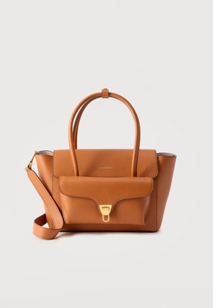 Taske i tanfarvet læder med to håndtag, frontlomme med flap og guldlås samt aftagelig skulderrem på ensfarvet baggrund.