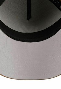 White and black baseball cap viewed from underside, showing stitching details and mesh inner lining.