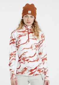 Langärmliges, weißes Fleece-Oberteil mit rotem Marmor-Muster, Halbreißverschluss, weiche Textur, kombiniert mit einer braunen Strickmütze mit Logo-Patch.