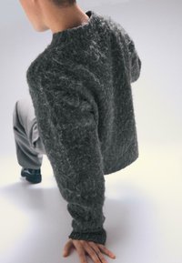 Hrubý, šedý sveter s voľným strihom, textúrovaným povrchom, rebrovanými manžetami, okrúhlym výstrihom a kontrastným detailom z mäkkej látky.